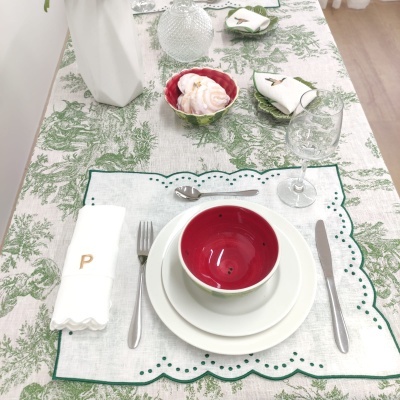 Conjunto de mesa com pratos, tigela vermelha, talheres, copo de vidro, guardanapo branco bordado com P, placemat branco e toalha de mesa verde e branca