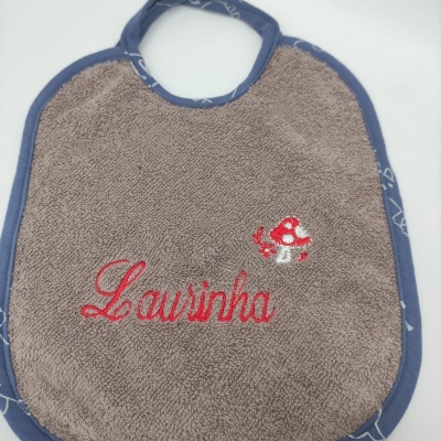 Babete castanho com borda azul e bordado vermelho 'Lausinha' e cogumelo pequeno.