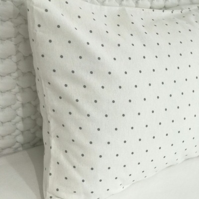 Almofada branca com pontos cinza sobre tecido branco trançado