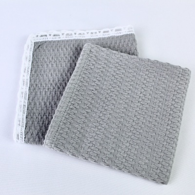 Toalhas cinzentas com textura trançada e borda branca em fundo branco.