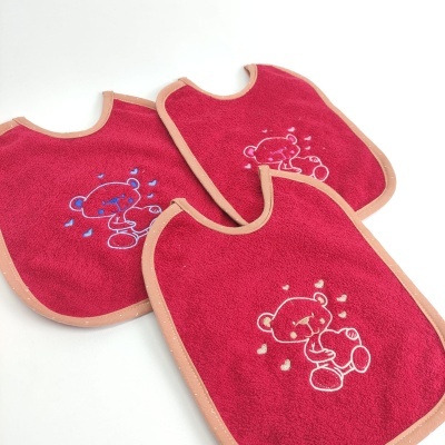 Três babetes vermelhos com ursinhos bordados e borda rosa sobre fundo branco