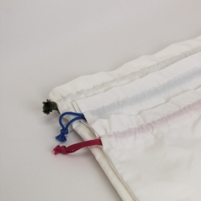 Três sacos de tecido branco com cordões coloridos pretos, azuis e vermelhos