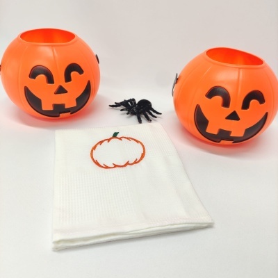 Baldes de abóbora, aranha de plástico e pano branco com bordado de abóbora