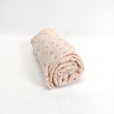 Tecido rosa claro com padrão de pequenas flores vermelhas enrolado