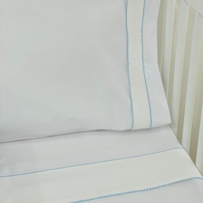 Roupa de cama branca para berço com detalhes bordados azuis