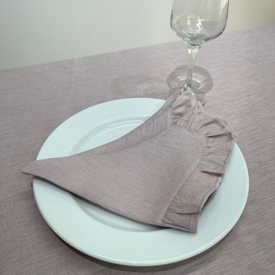 Mesa posta com prato branco, guardanapo rosa claro e copo de vidro