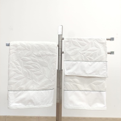 Toalhas de banho brancas com padrão de folhas penduradas em suporte metálico