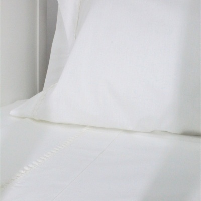 Conjunto de roupa de cama branco com almofada e lençol com detalhe bordado