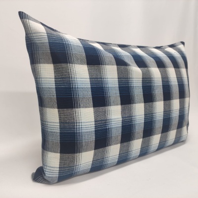 Almofada retangular azul e branca xadrez sobre superfície branca