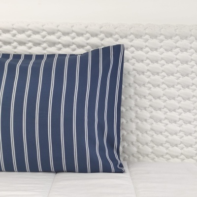 Almofada azul às riscas sobre sofá branco texturizado