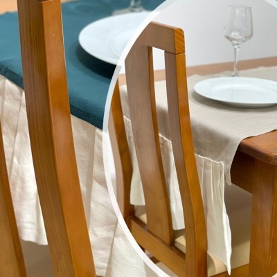 Cadeira de madeira com toalha de mesa bege e pratos brancos numa mesa de madeira