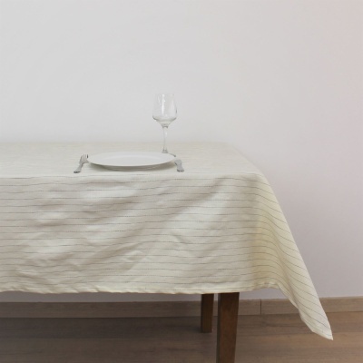 Mesa com toalha bege com riscas finas, prato branco, talheres e copo de vidro