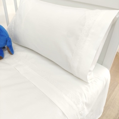 Jogo de cama branco com bordados delicados em cenário minimalista