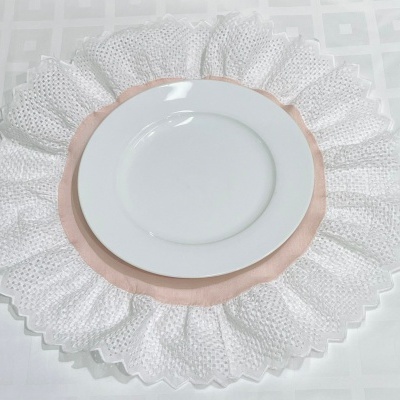 Prato branco sobre suporte de tecido rosa e branco bordado rendado