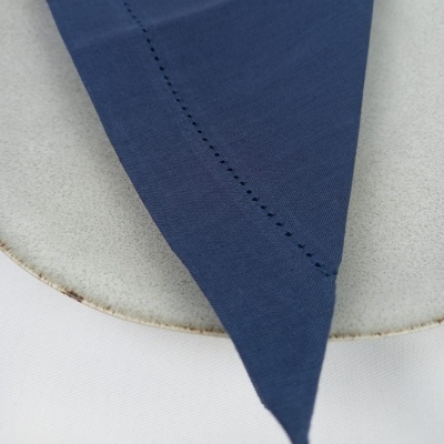 Guardanapo azul escuro sobre prato cinzento com borda irregular