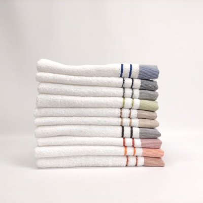 Conjunto de 10 toalhas brancas com riscas coloridas empilhadas
