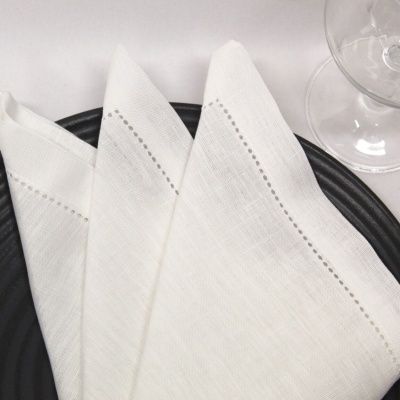 Guardanapos de tecido branco sobre prato preto e taça de vidro