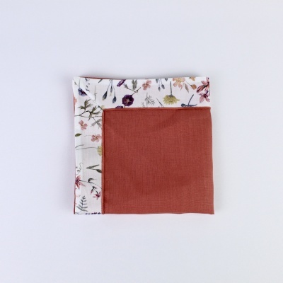 guardanapo de tecido com padrão floral de um lado e tecido liso terracota do outro
