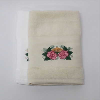 Duas toalhas de banho em algodão com bordado floral colorido sobre uma superfície branca