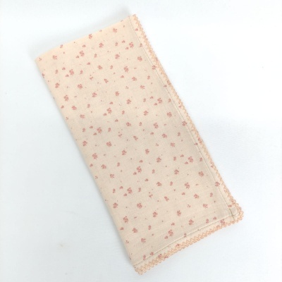 Pano de tecido bege claro com flores pequenas cor-de-rosa e borda decorativa