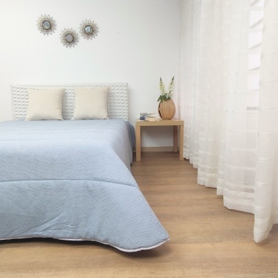 Quarto com cama azul clara, mesa de cabeceira madeira e decoração minimalista