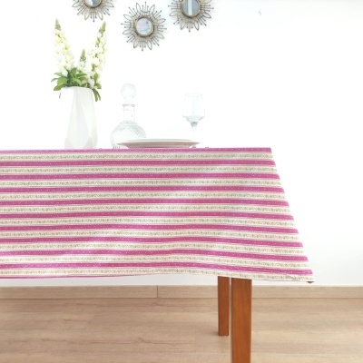 Toalha de mesa riscada rosa, bege e dourado sobre mesa de madeira