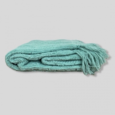 Manta azul esverdeada dobrada com franjas