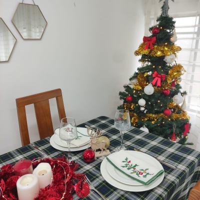 Mesa de Natal com decoração e árvore de Natal ao fundo