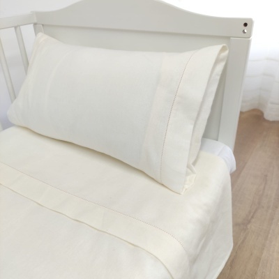 Jogo de cama creme em cama branca de madeira com fundo claro