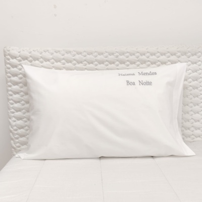 Travesseiro branco com fronhas bordadas em cama branca