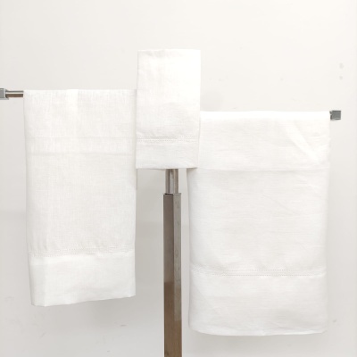 Conjunto de três toalhas brancas penduradas em suportes metálicos