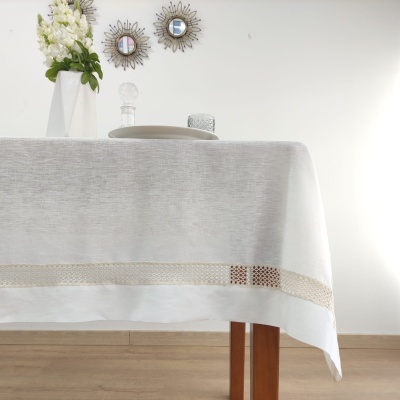 Toalha de mesa branca com bordado bege numa mesa de madeira