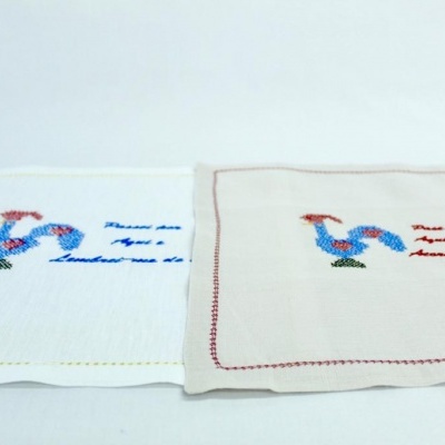 Dois panos de cozinha bordados com galinhas e texto, um branco e outro bege.