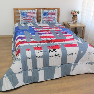 Cama de casal com edredão e almofadas com padrão de riscas e letras em cores vermelho, branco e azul