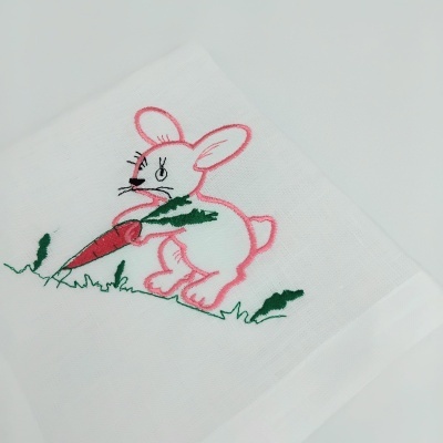 Toalha branca com coelho bordado segurando cenoura.