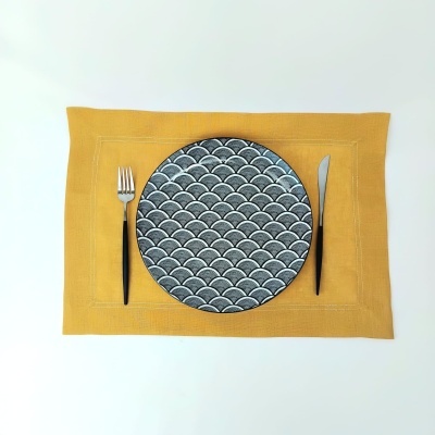 Prato com padrão de escamas cinzentas em individual amarelo mostarda com talheres pretos