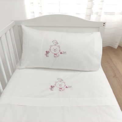 Jogo de cama infantil branco com bordado de ursinho rosa num berço branco