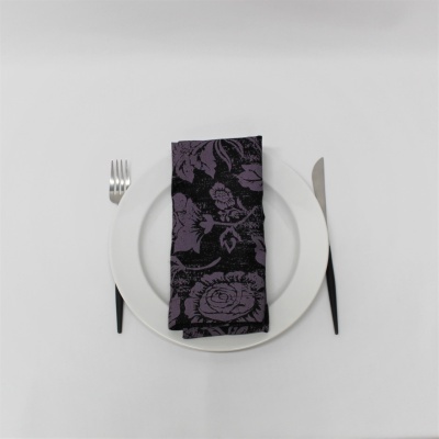 Prato branco com guardanapo floral roxo e preto e talheres com cabo preto