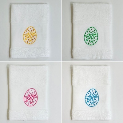 Quatro toalhas de banho brancas com bordados coloridos de ovos de Páscoa.
