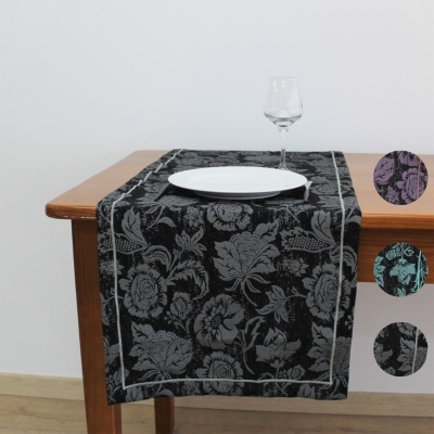 Caminho de mesa floral cinzento sobre preto numa mesa de madeira com prato branco e copo de vidro