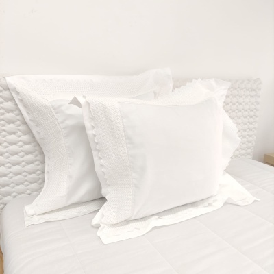 Conjunto de almofadas brancas em cama com cabeceira acolchoada branca