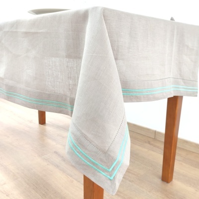 Toalha de mesa em linho cinza com linhas azuis claras nas bordas numa mesa de madeira