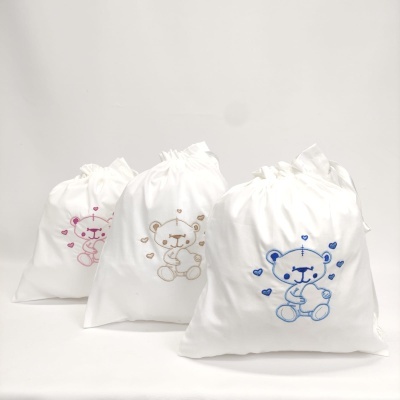 Três sacos de algodão brancos com ursinhos bordados em cores diferentes.