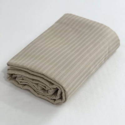 Manta beige com riscas verticais dobrada em superfície branca