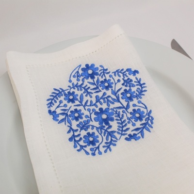 Guardanapo branco com bordado azul floral sobre prato branco