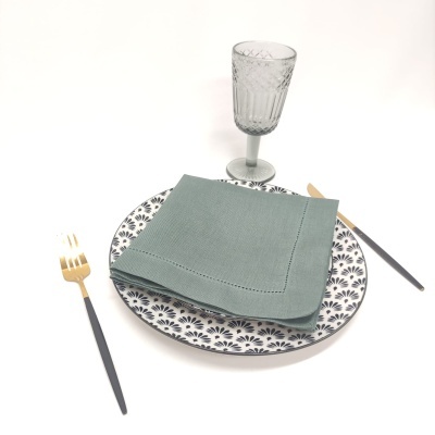 Conjunto de jantar com prato decorado, guardanapo verde, talheres e copo de vidro