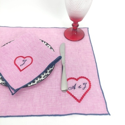 Lugar americano rosa com guardanapo e copo vermelho com faca