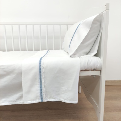 Cama branca com roupa de cama branca e detalhes em azul claro