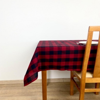 Mesa com toalha de mesa xadrez vermelho e preto, cadeira de madeira, prato e talheres