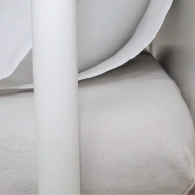 Cama de bebé branca com colchão claro e tecido branco ao fundo